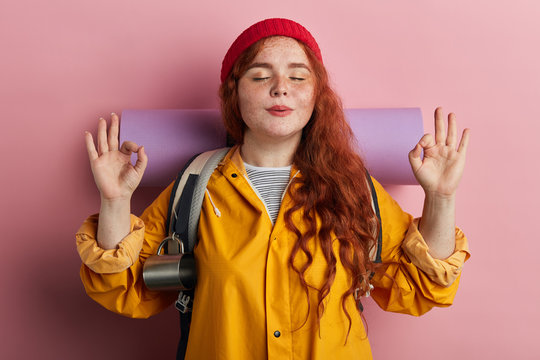 funny plump hiker with freckled having a rest during travel. close up photo. health care, tourist wearing crea mat, backpack doing yoga. meditation