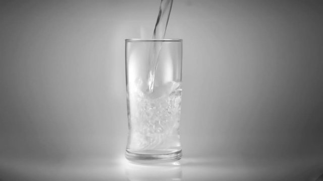 pour water into the glass in a white scene