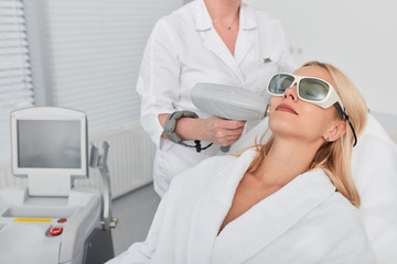 Naklejka premium female client wearing glasses and white bathrobe resting in beauty clinic. close up photo