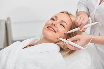 cheeful smiling awesome blonde woman having microcurrent medicine treatment. aesthetic peeling.close up photo. beauty, wellness and wellbeing