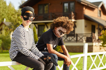 Portrait of two teenage boys wearing Halloween costumes posing outdoors and looking at camera, copy...