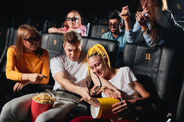 blonde guy splitting popcorn to his girlfriend's knees while watchin film. close up photo