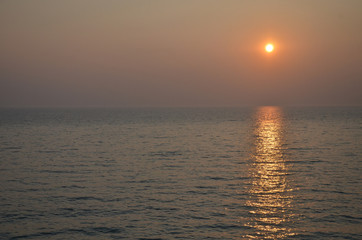 Empty sea to the horizon, evening. The sun is approaching the horizon, a light path is visible on the water.
