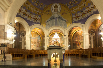Fototapeta na wymiar Lourdes, France, 24 June 2019: Interior of the Rosary Basilica, mosaic with the inscription 