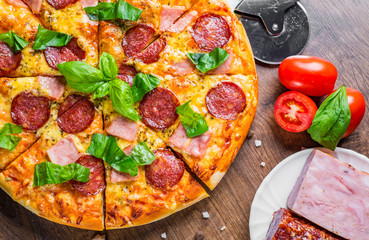 Pepperoni Pizza with Mozzarella cheese, salami, ham, Spices and Fresh basil. Italian pizza on wooden table background