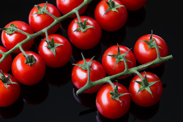 Fresh cherry tomatoes on a black background. Bunch of fresh cherry tomato on a black background