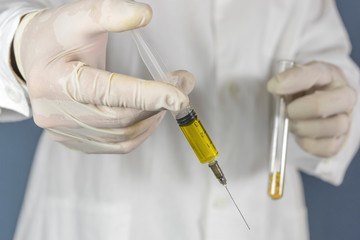 The researcher holds a test tube with soybeans and a syringe. GMO concept. Selective focus