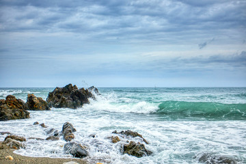 Fototapeta na wymiar Waves crashing against the rocks by the beach