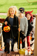 Full length portrait of children trick or treating on Halloween standing on stairs in row, focus on...