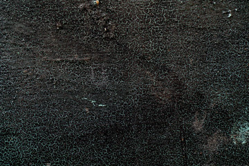 Metal texture covered black paint. Net of green cracks. Rough surface. Black background for text and design