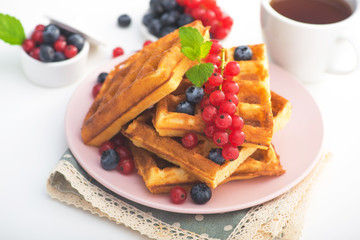 Sweet dessert belgian waffles with blueberry and red currant and tea drink