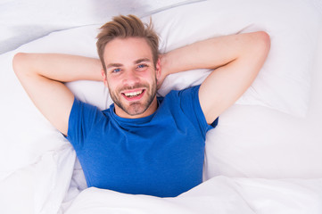 New smile, new day. Happy man awaken in bed. Handsome caucasian man with happy smile relaxing in...