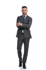 Young man wearing suit and tie stands with hands crossed