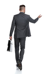 rear view of a  businessman holding briefcase and points hand