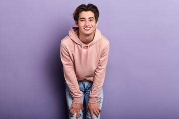 Handsome young cheerful smiling man in pink fashion sweater, isolated on blue background.close up photo. people, lifestyle,copy space.