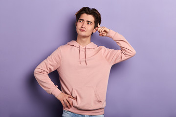 thoughtful serious guy with a hand on hip touching his head, trying to remember something, solve...