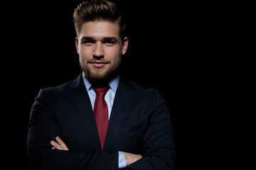 elegant businessman folding arms on black background