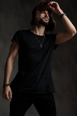 handsome young man holding hand on hat on grey background