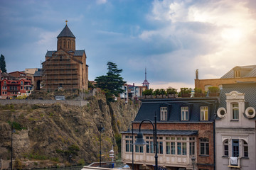 The old part of the city of Tbilisi. Wooden house and Metekhi church on a cliff.