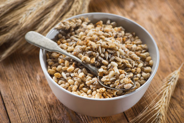 Tasty crispy granola in bowl with seeds and wheat on a wooden table