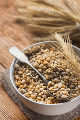 Tasty crispy granola in bowl with seeds and wheat on a wooden table