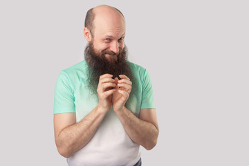 Portrait of cunful funny middle aged bald man with long beard in light green t-shirt standing,...