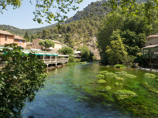 Fototapeta na wymiar France, july 2019: Beautiful medieval village Fontaine de Vaucluse on the river shore. The poet Petrarch made it his preferred residence in the 14th century