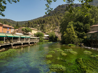 Fototapeta premium France, july 2019: Beautiful medieval village Fontaine de Vaucluse on the river shore. The poet Petrarch made it his preferred residence in the 14th century