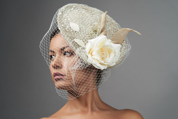 Elegant woman portrait in retro hat. Beautiful bride over grey background