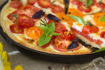 Tomato tart made with shortcrust  pastry, red and yellow tomatoes, cheese and cream. Concept of healthy eating or vegetarian food on rustic wooden background