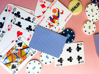 Chips and cards for poker on pink background.