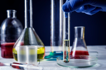 Close-up of glass tube with blue fluid in scientist hand during medical test