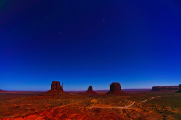 View of Monument Valley at night with lots of stars in the sky in Navajo Nation Reservation in USA.
