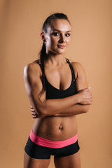 Fototapeta na wymiar Young muscular woman bodybuilder with perfect athletic body in black sportswear is standing with arms folded, on pink red isolated background. Sporty beautiful female looking at camera