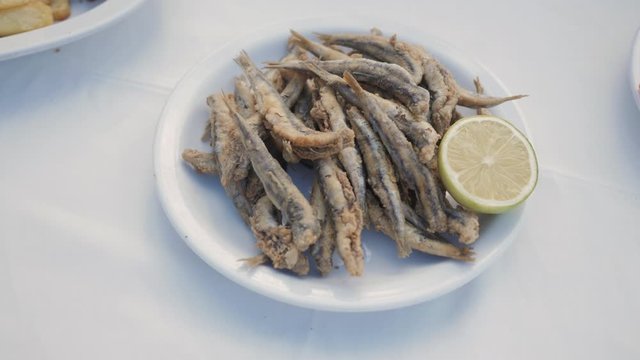 Fried anchovies with fresh lemon served on a white dish on a greek tavern table. La Canea, Chania, Crete, Greek islands.