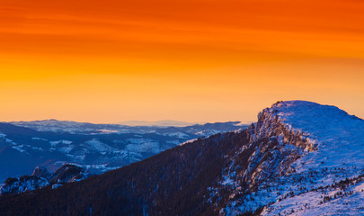 golden sunset in winter mountain landscape. Ceahlau, Romania