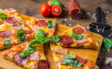 Pepperoni Pizza with Mozzarella cheese, salami, ham, Spices and Fresh basil. Italian pizza on wooden table background