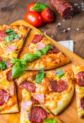 Pepperoni Pizza with Mozzarella cheese, salami, ham, Spices and Fresh basil. Italian pizza on wooden table background