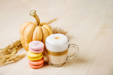Pumpkin Spice Latte. Cup of Latte with Pumpkin, Macaroons  and Fall Decor. Traditional Autumn Coffee Drink with cookies..
