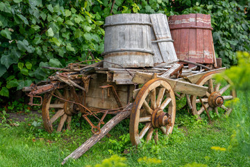 Fototapeta na wymiar alter hölzerner Wagen mit 3 Wasserbottichen auf Rädern im Freien