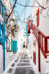 Fototapeta na wymiar Typical Greek architecture in the white, cobbled alleys of Mykonos town, houses in the old town of Chora with colorful balconies and white churches, Cyclades, Greece