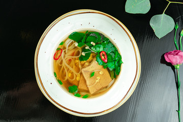 Traditional vietnamese and tasty pho bo - noodle soup with mint, beef and hot pepper in white bowl...