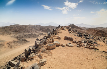 Brown sand, desert dunes and hills on blue sky background. Rough roads with vehicle tracks on dry, sandy land surface on sunny day. Travel destination and vacation