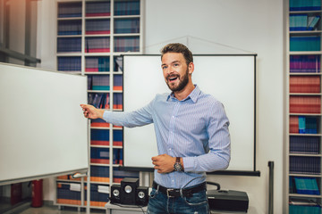 Smiling male coach giving presentation for audience in lecture hall