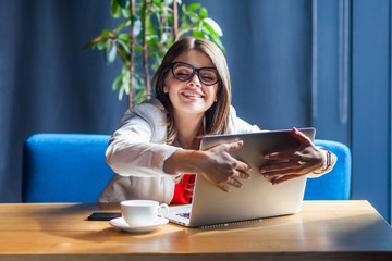 Portrait of happy satisfied beautiful stylish brunette young woman in glasses sitting and hug her favorite laptop with love and toothy smile. indoor studio shot, cafe, office background.