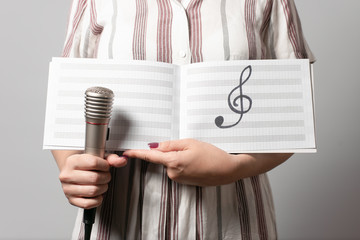 Music book with a copy space and microphone in a woman hands.