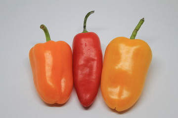 Side View of Red, Orange and Yellow Mini Sweet Peppers on a White Background