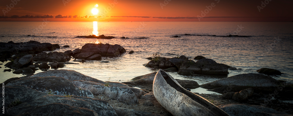 Wall mural sunrise view at the lake malawi, waves rolling smoothly on the beach, wooden one tree boat in the fo