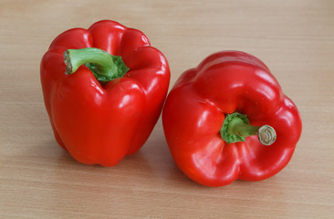 Two whole red peppers on a table