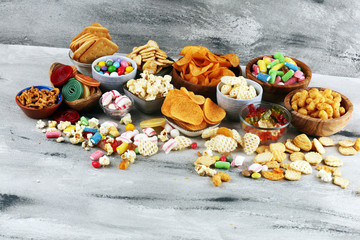 Salty snacks. Pretzels, chips, crackers and candy sweets on table